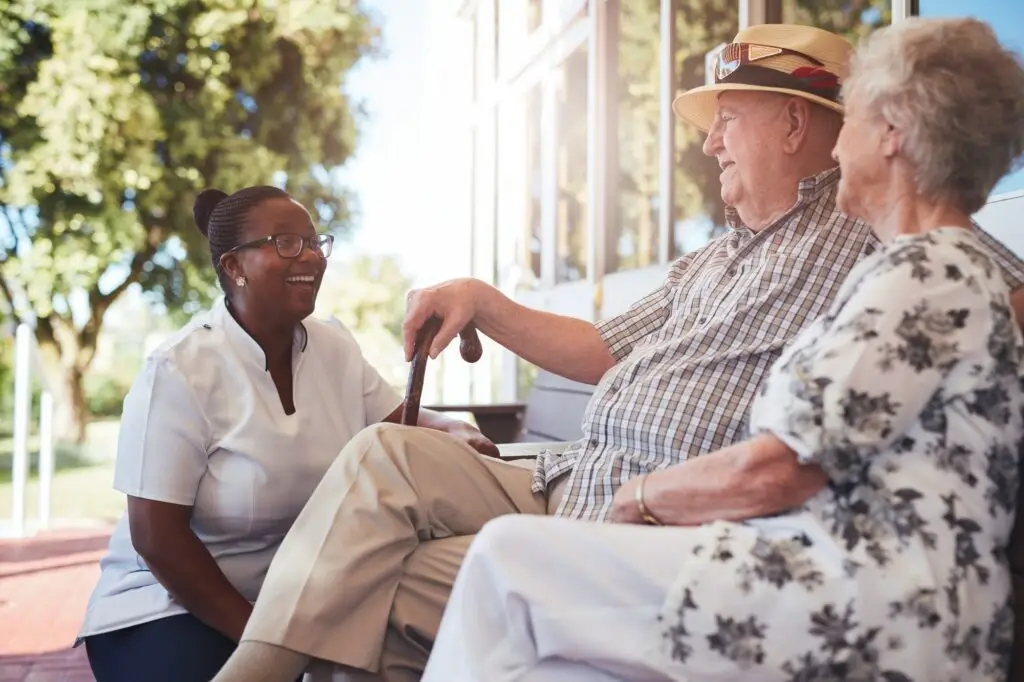 Senior couple with caregiver sitting outside